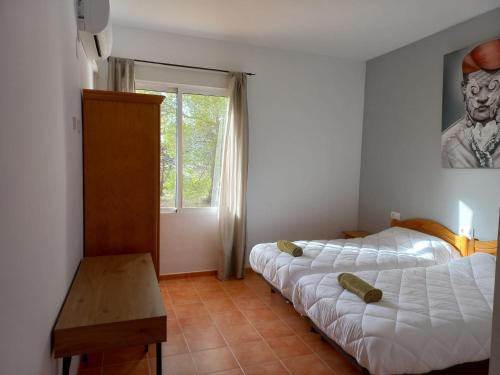a bedroom with two beds and a table and a window at ECORESORT LOS SUEÑOS DEL JÚCAR Complejo la Fuente in Casas de Ves