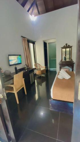 a bedroom with a bed and a desk and a chair at Rahayu Guest House Seminyak in Seminyak