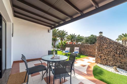 a patio with a table and chairs and a stone wall at VV Makita by HH in Playa Blanca