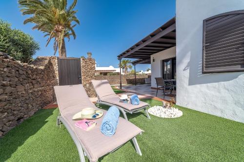 a backyard with two chairs and a patio with grass at VV Makita by HH in Playa Blanca