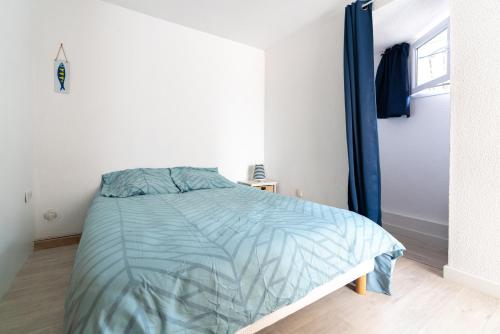 een slaapkamer met een bed met een blauw dekbed bij Maison de pecheur la rose des vents in Valras-Plage