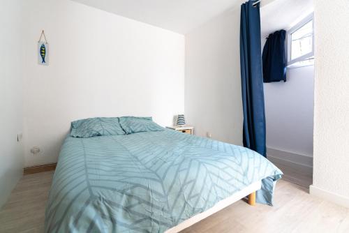 a bedroom with a bed with a blue comforter at Maison de pecheur la rose des vents in Valras-Plage