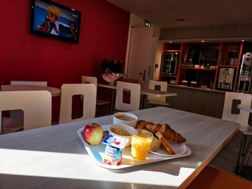 a table with a tray of breakfast foods and orange juice at Première Classe Metz Nord - Talange in Talange