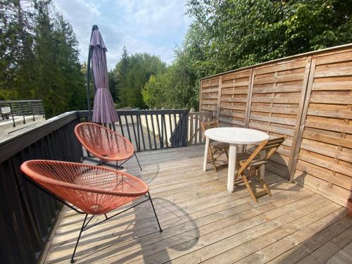 a deck with two chairs and a table and an umbrella at Studio 8 in Sancourt