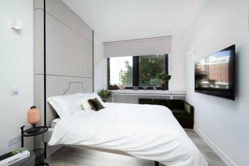 a bedroom with a white bed and a window at Spacious Studio Apartments at Dandi on The Hill in Harrow