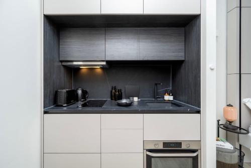 a kitchen with black and white cabinets and a stove at Spacious Studio Apartments at Dandi on The Hill in Harrow