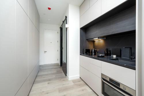 a kitchen with white cabinets and black counters at The Hill by Nestor in Harrow