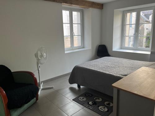 1 dormitorio con 1 cama, 1 silla y ventanas en Appartement centre historique, en Blois