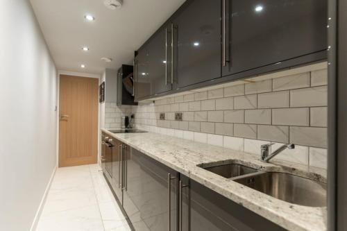 a kitchen with a sink and black cabinets at Billie Island apartments in Slaithwaite