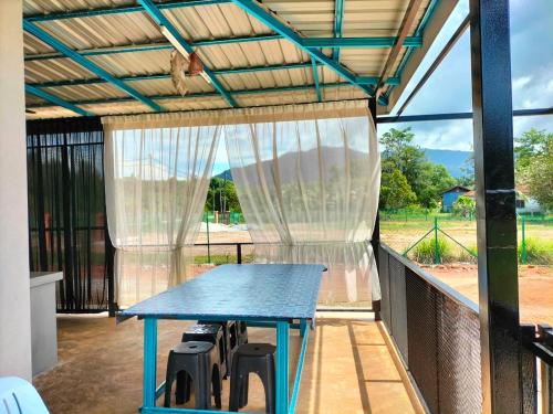 a patio with a blue table and chairs on a balcony at De Hampar Homestay in Kampong Merbok