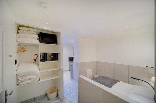 - une salle de bains blanche pourvue d'un lavabo et de serviettes sur les étagères dans l'établissement JOLI STUDIO AVEC TERRASSE CANNES CENTRE a0b169, à Cannes