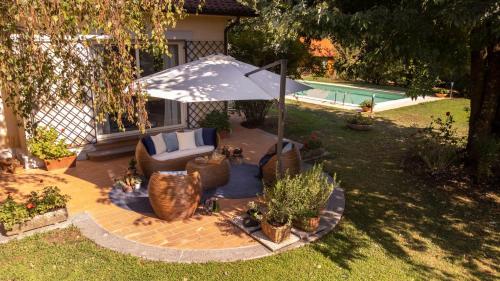 a patio with a couch and an umbrella and some plants at VILLA SPRECA_Un'elegante oasi di pace in Capranica