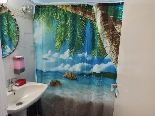 a bathroom with a shower curtain with a view of the ocean at Διαμέρισμα 110 Μ στον Λαγκαδά in Lagadas