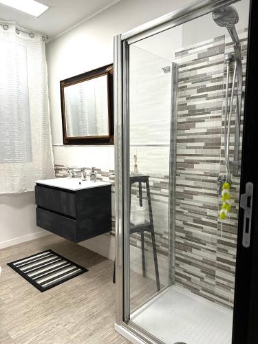 a bathroom with a glass shower and a sink at Le Mandorle Apartment in Belpasso