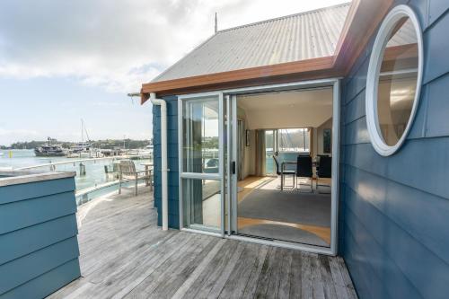 a house with a large glass door on a deck at Bay of Islands Apartment On The Water- The Bridge in Opua