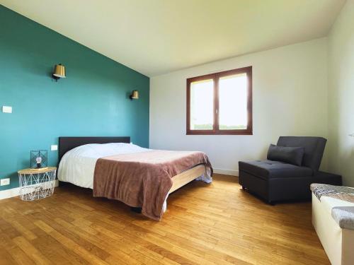 a bedroom with a bed and a chair at Le Robinson - Jusqu'à 7 couchages in Bourg-Fidèle