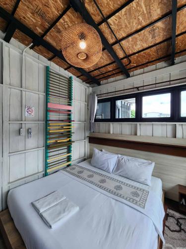 a bedroom with a white bed in a room with windows at Baan Mai Kradan Hostel Chiang Rai in Chiang Rai