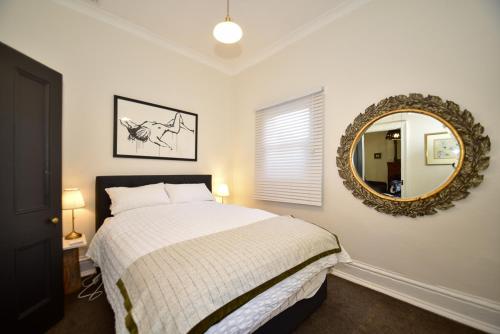 a bedroom with a bed and a mirror at Macleay Cottage with plunge pool and local arts in Dubbo