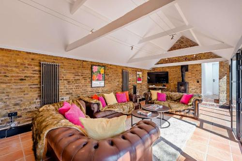 a living room with leather furniture and a brick wall at The Willows by Bloom Stays in Ash