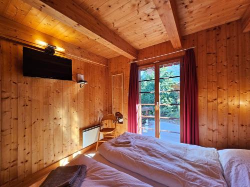 サースフェーにあるChalet Flairの窓付きの木製の部屋のベッド1台が備わるベッドルーム1室を利用します。