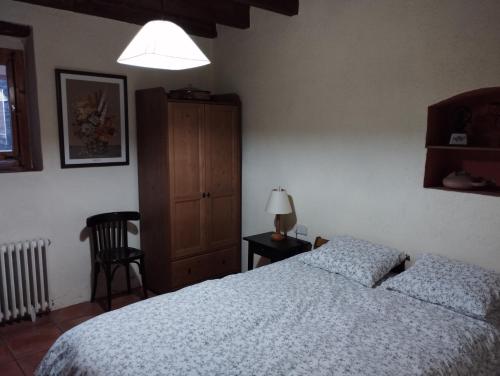 um quarto com uma cama, um armário e um candeeiro em Llar compartida El Tupí em Sant Juliá de Vilatorta