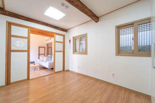 private house JNP stay في سول: غرفة معيشة فارغة بجدران بيضاء وسقوف خشبية