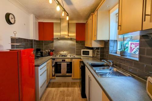 uma cozinha com um frigorífico vermelho e um lavatório em Brighton Parlourama with Hot Tub - Sleeps 18 em Brighton & Hove