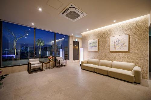 a living room with a couch and a large window at Brown Dot Hotel Daegu Suseong in Daegu
