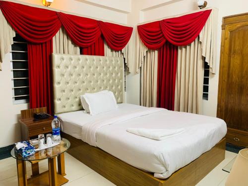 a bedroom with a large bed with red curtains at Hotel Heaven Inn in Dhaka