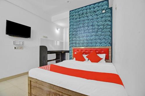 a bedroom with a bed with a red headboard and a television at OYO Flagship Jamtha Hotel Guest House in Nagpur