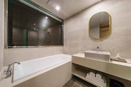 a bathroom with a tub and a sink and a mirror at Brown Dot Hotel Daegu Suseong in Daegu