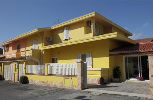 żółty dom z białym płotem w obiekcie B&B Terre del Sinis w mieście Cabras