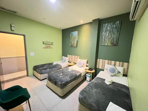 three beds in a room with green walls at The Tree Boutique Hotel in Shah Alam