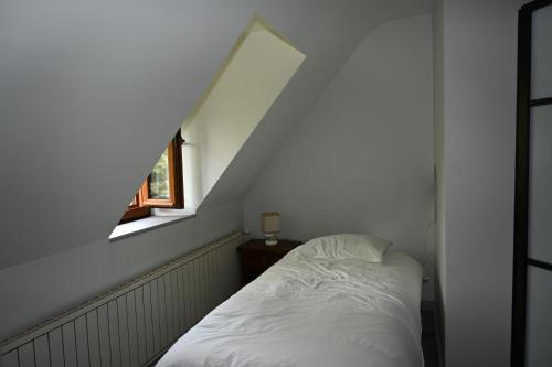 a bedroom with a white bed and a window at La Villa du Papetier in Boussières