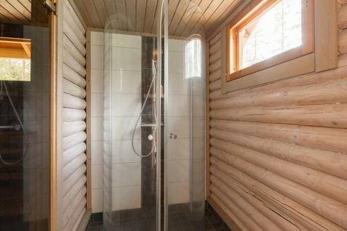 eine Dusche im Bad mit Holzwänden und einem Fenster in der Unterkunft Cottage with Hot tub and Sauna in Uurainen