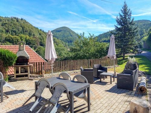 eine Terrasse mit einem Tisch, Stühlen und einem Grill in der Unterkunft Les Sapins in Bussang