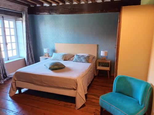 a bedroom with a bed and a blue chair at Gîte Design in Arceau