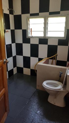 a bathroom with a toilet and a black and white checkered wall at Roomstay "Ghumah Uwan" in Batu Kikir