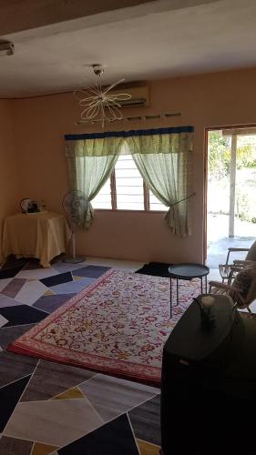 a living room with a rug on the floor and a window at Roomstay "Ghumah Uwan" in Batu Kikir