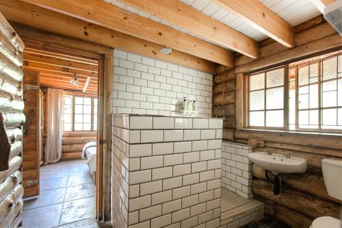 baño con paredes de madera y lavabo blanco en Mountain Canadian Log Home, en Kalkheuvel