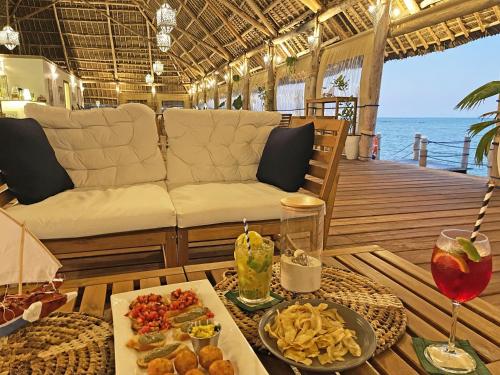 une table avec de la nourriture et un canapé sur une terrasse dans l'établissement Pongwe Bay Resort, à Pongwe