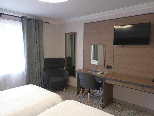 a hotel room with a desk and a television at Corn Mill Lodge Hotel in Leeds