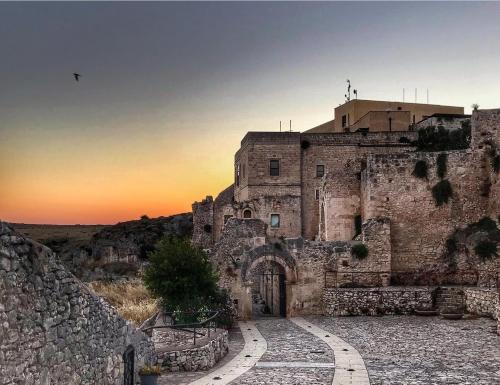 un antiguo edificio de piedra con una puesta de sol en el fondo en Casetta a Monte Sant'á, en Monte SantʼAngelo