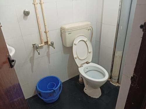 a bathroom with a toilet and a blue bucket at Hotel Ambika Palace in Chennai