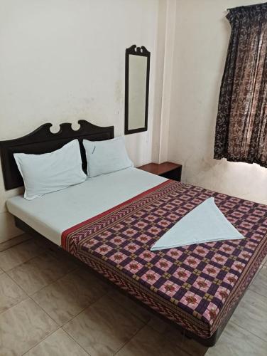 a bedroom with a bed with a comforter at Hotel Ambika Palace in Chennai