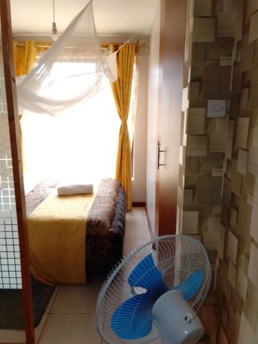 Zimmer mit einem Bett, einem Ventilator und einem Fenster in der Unterkunft Tsavo 90 degrees smart view in Nairobi