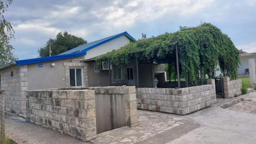 a house with a retaining wall and a fence at Apartments Airport Golubovci 2 in Podgorica