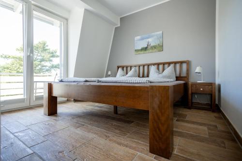 - une chambre avec un lit en bois dans une pièce dotée d'une fenêtre dans l'établissement DER STÖRTEBEKER - "Apartment Ahrenshoop" Apartments hinter den Dünen, à Dierhagen