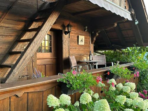 een veranda van een houten huis met een tafel en bloemen bij Hadassa Apartment Mutzli in Steffisburg