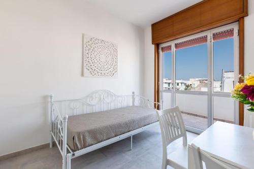 a white bedroom with a bed and a balcony at Residence Kalura by BarbarHouse in Porto Cesareo